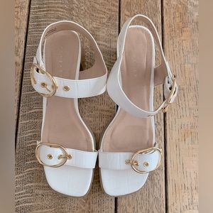 White sandals with gold detail.